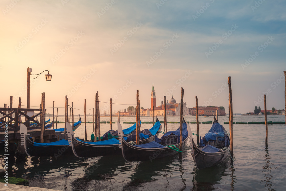 Gondolas on the pier. Cathedral of San Giorgio Maggiore on the background. Yearly Venetian morning