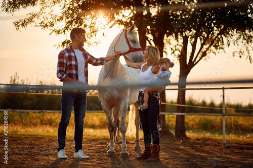 Family with child petting horses in countryside