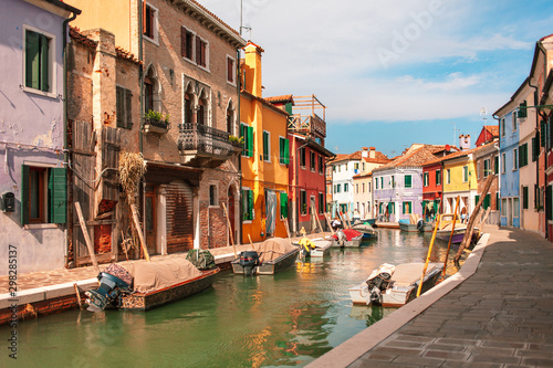 Traditional vibrant colored houses along chanal with boats on the island of Burano, Italy