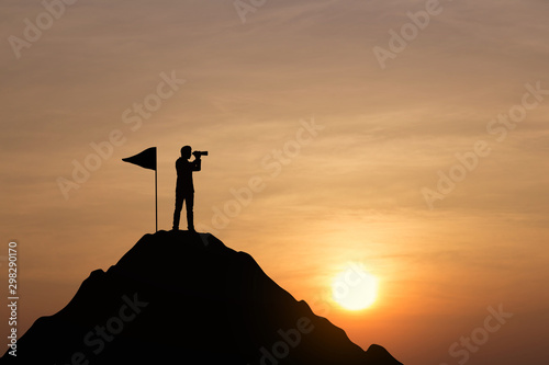 Silhouette of businessman on top of mountain at sunset background. Vision concept.