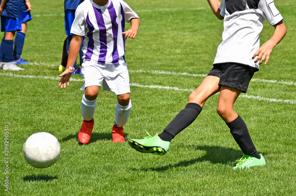 Young kids are playing soccer in summer time