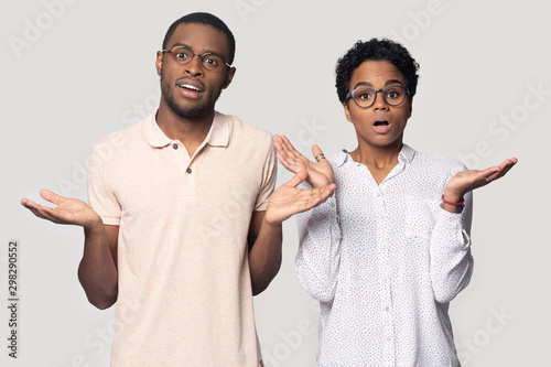 Head shot shocked African American man and woman shrugging shoulders