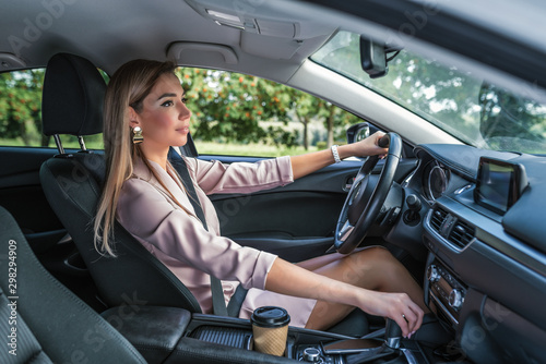 Beautiful girl business lady summer city car. Reversing, looking rearview mirror, engaging reverse gear, traffic jam parking lot. Car rental, car sharing. Automatic transmission. Autumn day nature. © byswat