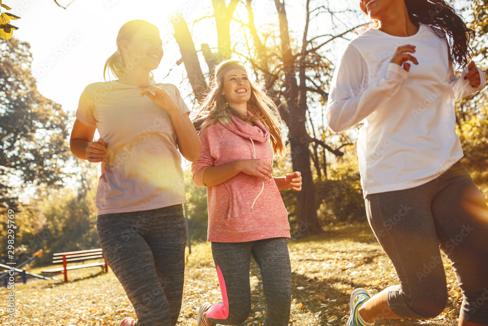 Group of female friends jogging at the city park in the morning.Autumn season. - obrazy, fototapety, plakaty 