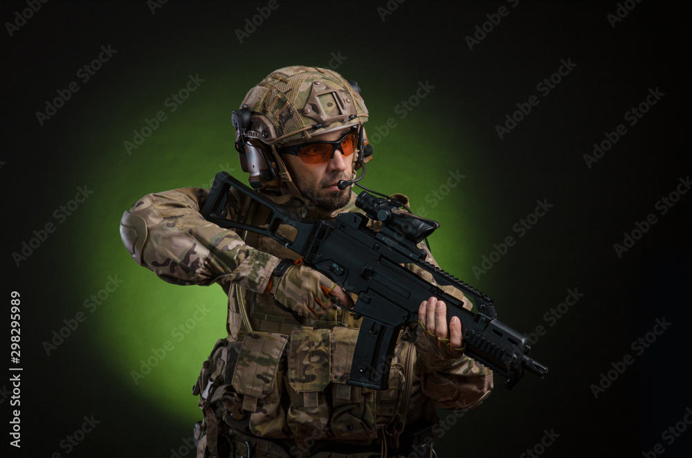 a male soldier in military clothes with a weapon on a dark background a male soldier in military clothes with a weapon on a dark background