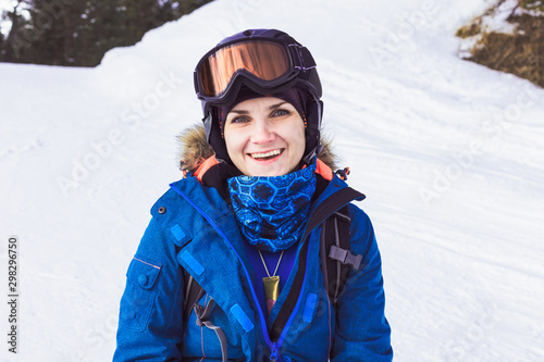 Portrait of beautiful woman in helmet and mask, snowboard suit in winter mountain.