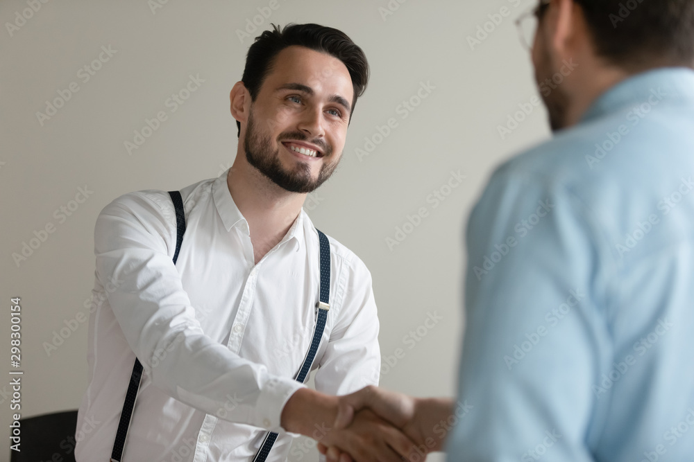 Smiling confident businessman shaking hand of business partner at meeting Smiling confident businessman shaking hand of business partner at meeting