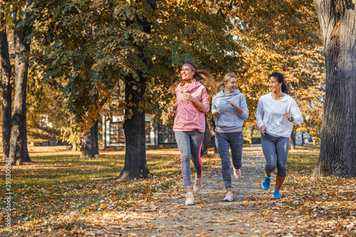 Fototapeta Naklejka Na Ścianę i Meble -  Group of female friends jogging at the city park.Autumn season.