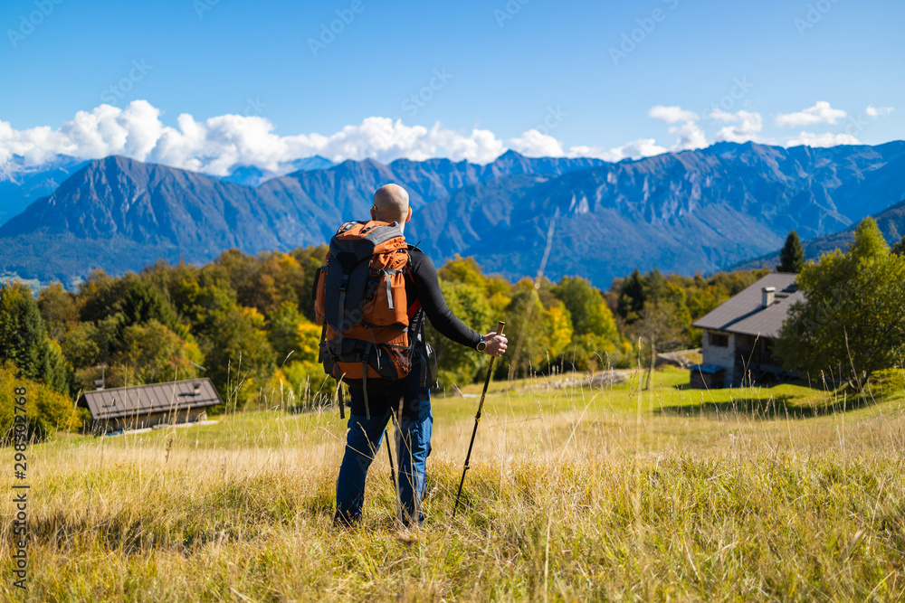 Tourist with a backpack stands on a hill of beautiful alpine landscape