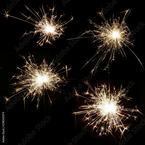 Set of four bright burning sparklers on a black background