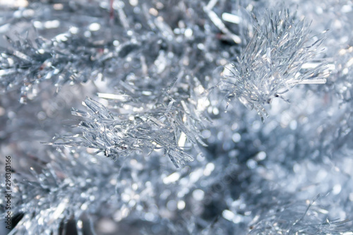 Silver artificial Christmas tree branches background. Selective focus. Closeup view. New Year's Eve home decoration