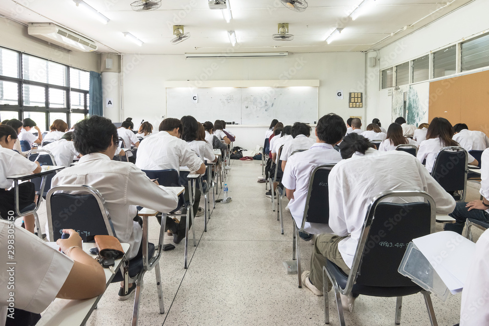 Exam with school students in class back view of the classroom of young people having stress doing examination admission test for university and college education background