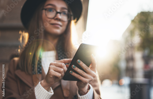 Young woman holding in hands mobile phone. Close up technology smartphone online communication. Girl traveler in hat using gadget cellphone in europe sunlight city. Digital internet lifestyle mockup