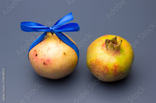 Fruta de Granada con un lazo azul como si fuese un regalo; fruta llena de vitaminas y antioxidantes photo