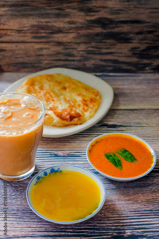 A cup of hot coffee , Roti canai or Roti Parata , dalca and curry sauce on wood background A cup of hot coffee , Roti canai or Roti Parata , dalca and curry sauce on wood background