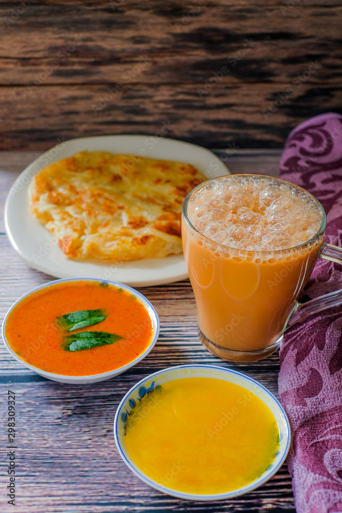 A cup of hot coffee , Roti canai or Roti Parata , dalca and curry sauce on wood background A cup of hot coffee , Roti canai or Roti Parata , dalca and curry sauce on wood background
