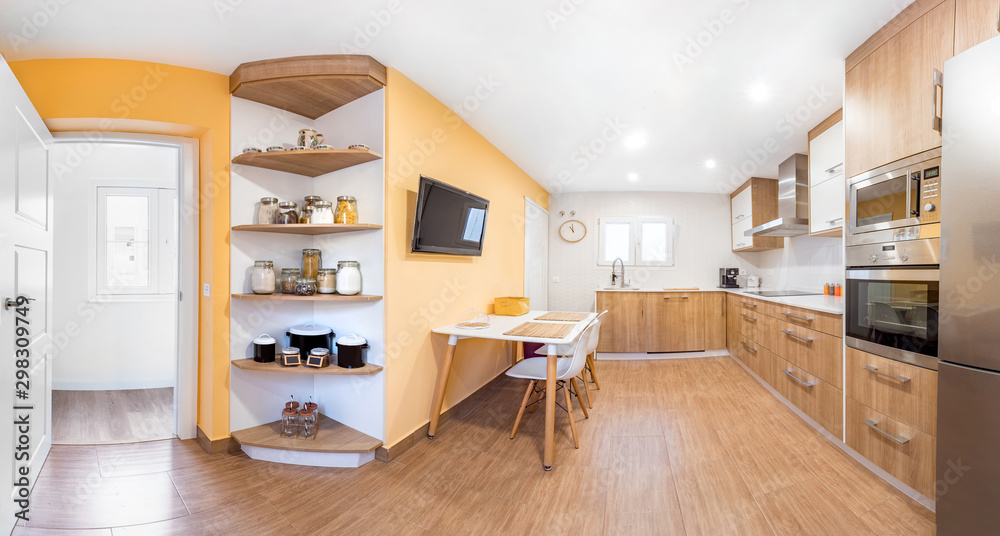 Panorama of a new stylish bright kitchen with wooden cabinets. Spacious modern interior with white table, chairs, television and big windows Panorama of a new stylish bright kitchen with wooden cabinets. Spacious modern interior with white table, chairs, television and big windows