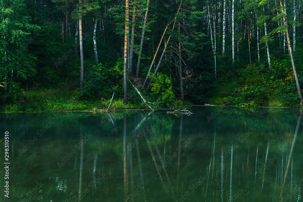Beautiful calm lake and dark emerald forest ashore