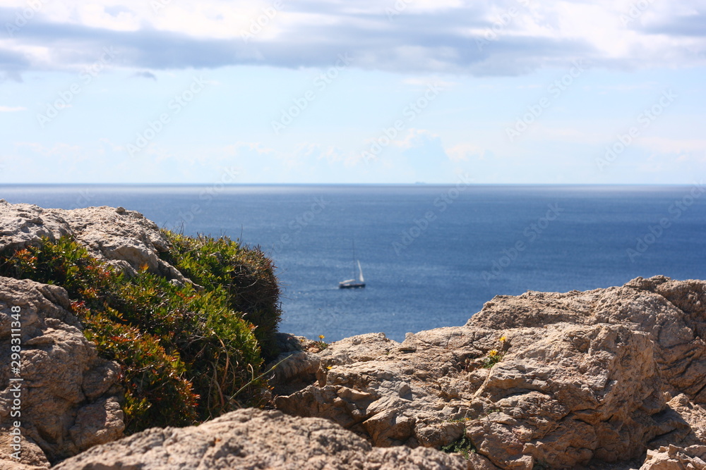 Steinige Küste mit blauem Meer und Schiff