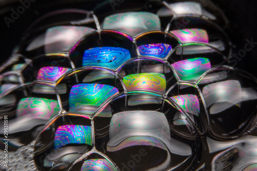 Close up of the Colorful bubbles on a black background. Refection of the Soap bubbles on the water surface on black background.