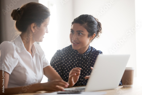 Senior female manager helping young smiling indian intern