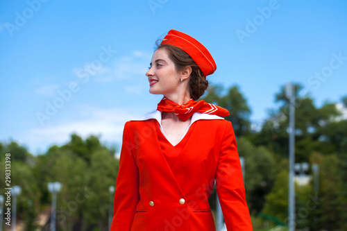 Beautiful stewardess dressed in official red uniform gainst a blue sky photo