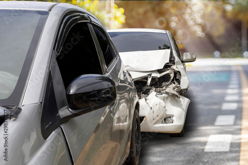 Front of white color car crash with back side of gray color car damaged and broken by accident on road.