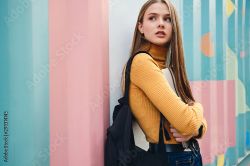 Beautiful pensive student girl with laptop thoughtfully looking away over colorful background