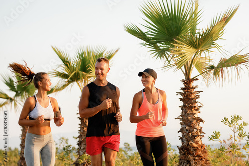 Group of athletic people communicating while jogging in nature.