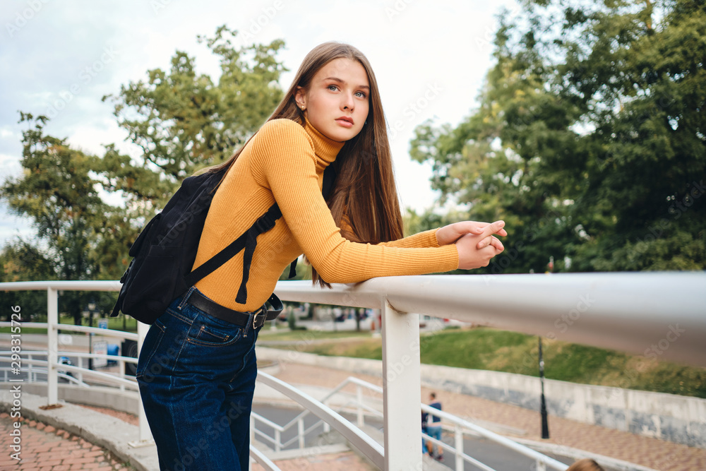 Beautiful casual student girl with backpack intently looking away in park Beautiful casual student girl with backpack intently looking away in park