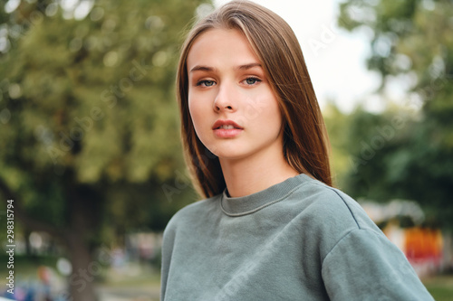 Portrait of beautiful pensive casual student girl thoughtfully looking in camera on street