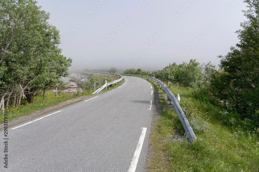 small road bending into fjord fog near Grunnfor, Norway