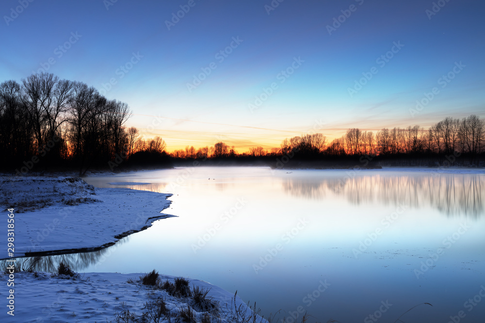 Winter landscape of trees and river in a foggy morning. Frost and cold and sunshine.