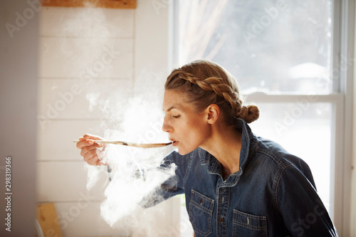 Slika na platnu Woman tasting food while cooking in kitchen