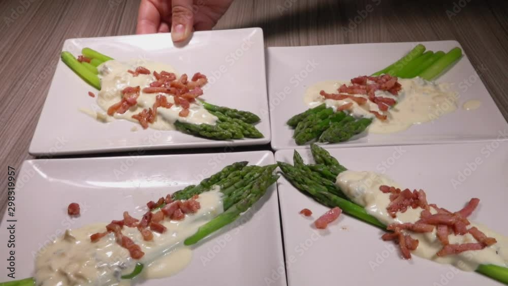 Square plate with asparagus in a cheese sauce with ham is put on the table with other plates. Beautiful serving of traditional French cuisine Square plate with asparagus in a cheese sauce with ham is put on the table with other plates. Beautiful serving of traditional French cuisine