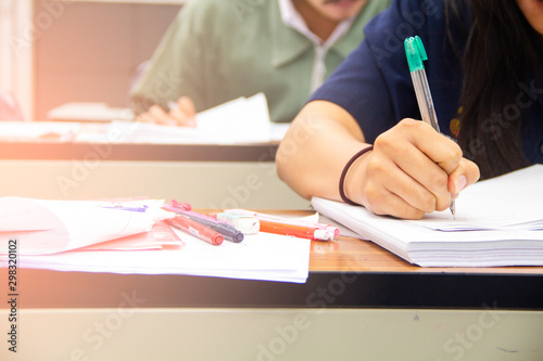 University students do quiz, test or studies from the teacher in a large lecture room. Students in uniform attending exam classroom educational school.
