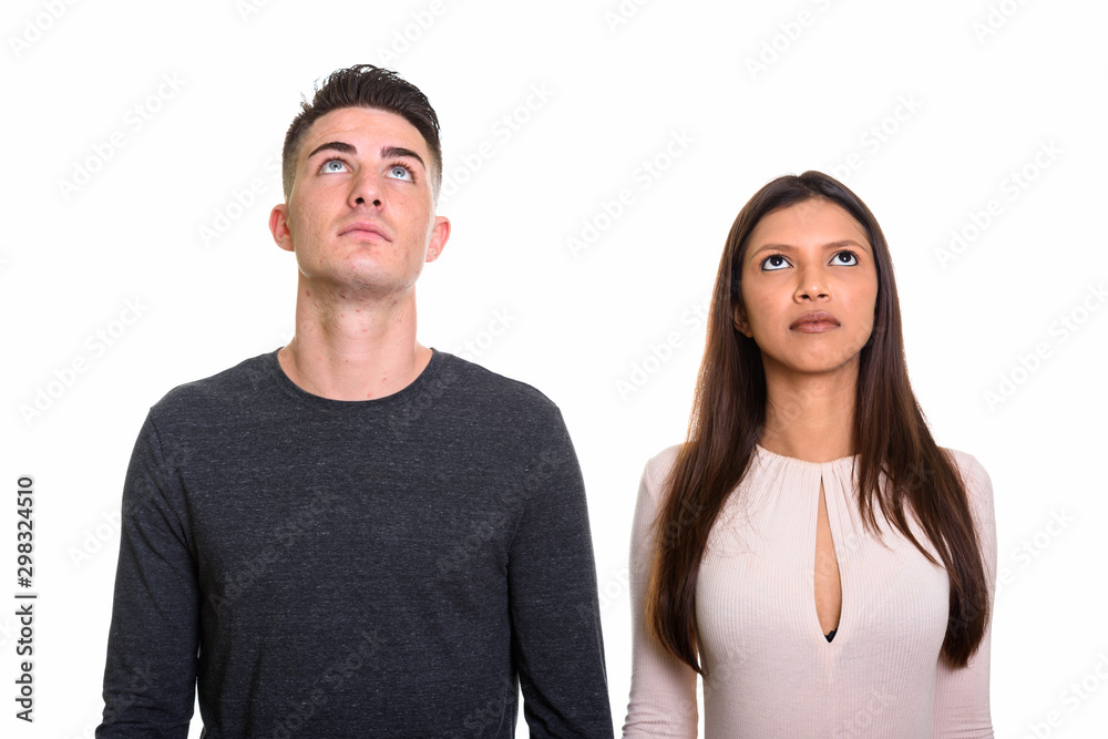 Studio shot of young couple looking up and thinking together Studio shot of young couple looking up and thinking together
