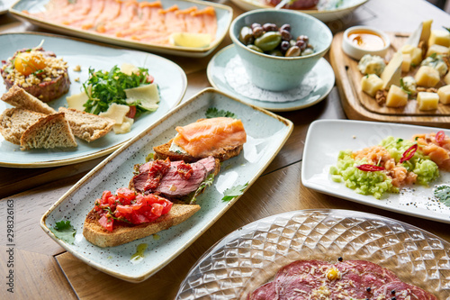 Bruschetta with beef, tomatoes and salmon.. Variety of dishes on the table. Various snacks and antipasti on the table. Restaurant menu. Italian cuisine