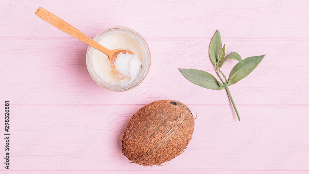 Ripe coconut, jar of oil near green leaves Ripe coconut, jar of oil near green leaves