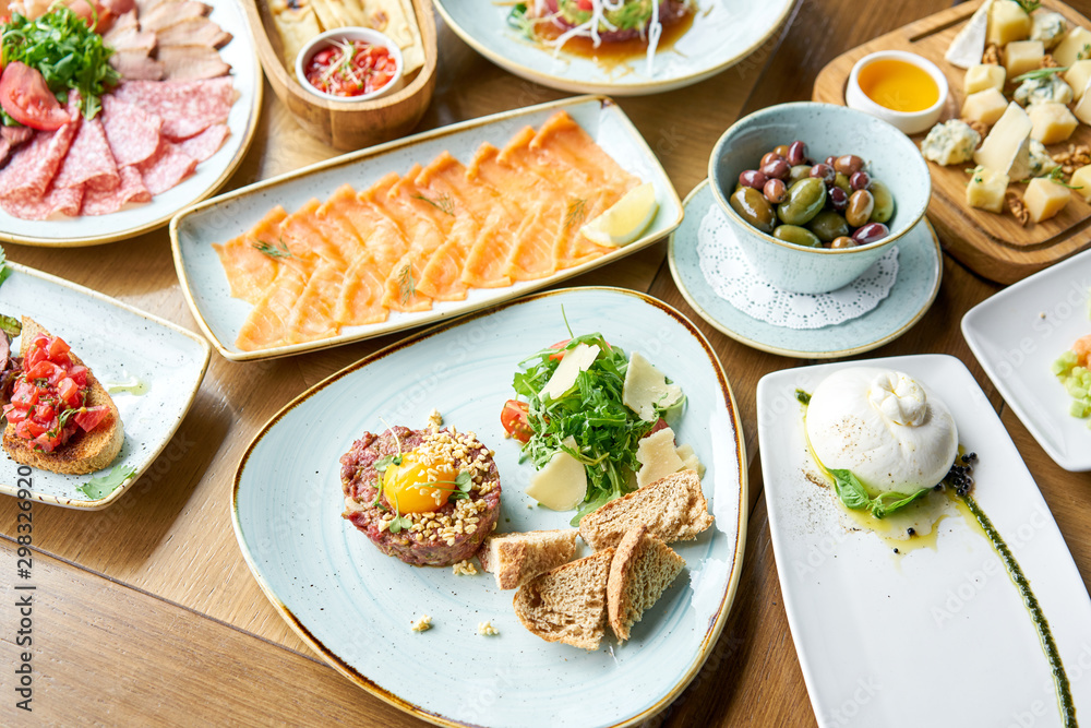 Beef tartar in the restaurant. Variety of dishes on the table. Various snacks and antipasti on the table. Restaurant menu. Italian cuisine