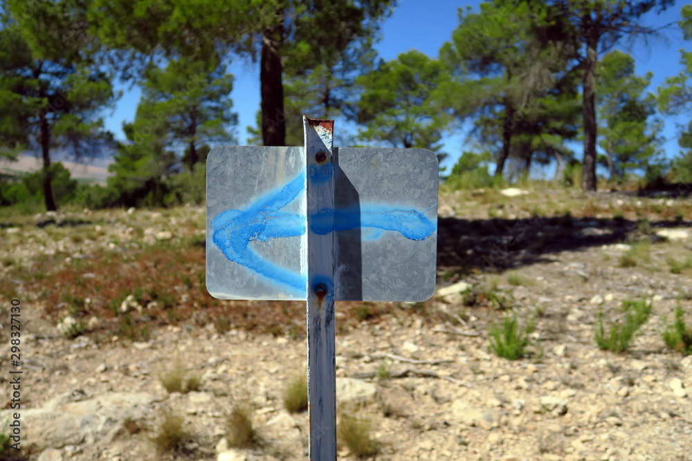 Panneau en fer avec flèche bleue peinte dirigée vers la gauche.
