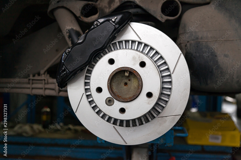 The braking system of the car with the wheel removed with the disc, pads, hub and cooling holes during maintenance and replacement in the workshop on the vehicle repair. Auto service industry.