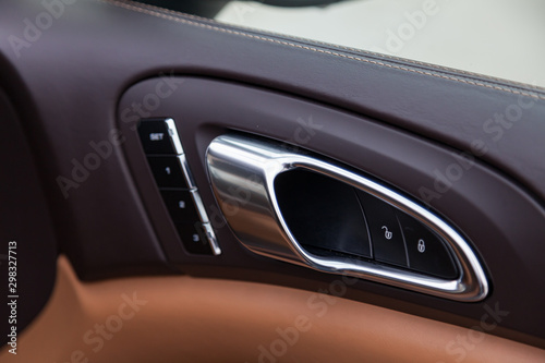 The interior of the car with a view of the dashboard, door handle and memory seat buttons with light brown leather trim © Aleksandr Kondratov