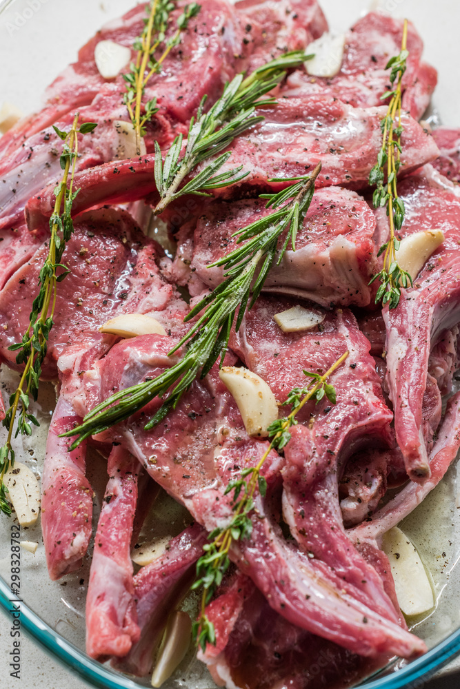 Raw Marinated Lamb Chops with Rosemary, Olive Oil and Garlic in Glass Bowl.