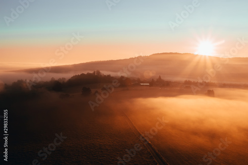 Aerial view to misty orange fog with path and hill at sunrise  Czech landscape
