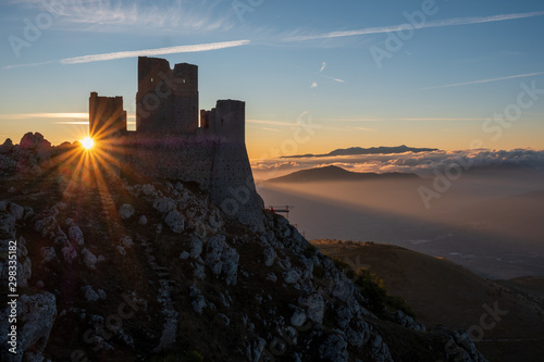 Ruins of medieval castle of Rocca Calascio at sunny morning, with foggy landscape in background and sunstar, Abruzzo, Italy photo