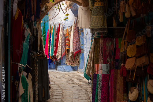 Narrow streets and blue painted houses of Chefchaouen city, Morocco. Most of the streets full of handmade colorful crafts,carpets and souvenir hanged to the walls of the blue houses.