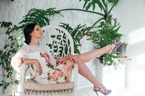 Portrait of a woman in a dress with flowers in a white room with homeplants photo