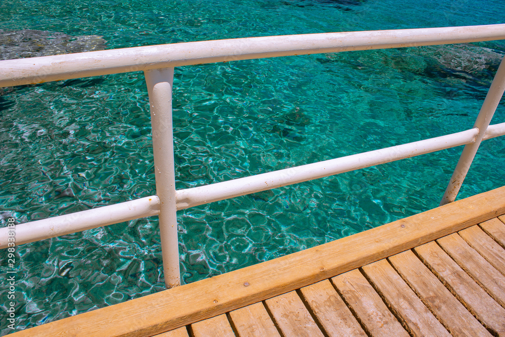 Fototapeta premium tropic outdoor environment wooden pier in poor Asian dock aquamarine transparent ripple water background surface with coral reefs bottom view on background