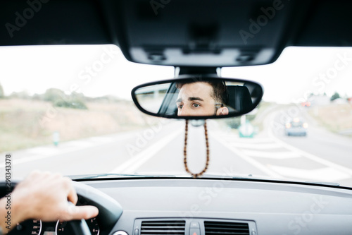 Young man driving a car, close up of rear mirror photo